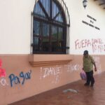 Un adulto mayor camina en una acera de un edificio público en la ciudad de León con sus paredes con pintas contra el dictador Daniel Ortega.